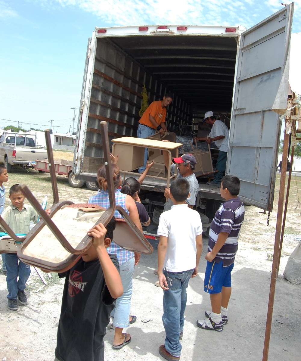 Unloading the donated school furniture with the lots of help.